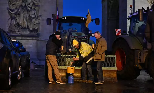 French farmers cook as they protest at the Arc de Triomphe against the Mercosur trade alliance with South America countries but also against EU farming policy or mass cull of cows ordered to contain the spread of a skin disease, Thursday, Jan. 8, 2026 in Paris. (AP Photo/Emma Da Silva)