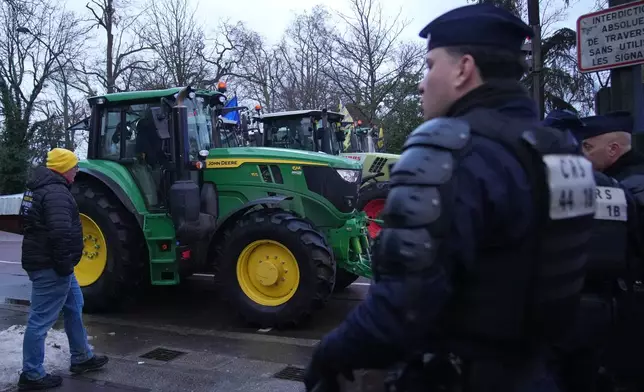 Police officer watch farmers at a blockade as farmers protest against the Mercosur trade alliance with South America countries but also against EU farming policy or mass cull of cows ordered to contain the spread of a skin disease in Paris Thursday, Jan. 8, 2026 in Paris. (AP Photo/Christophe Ena)