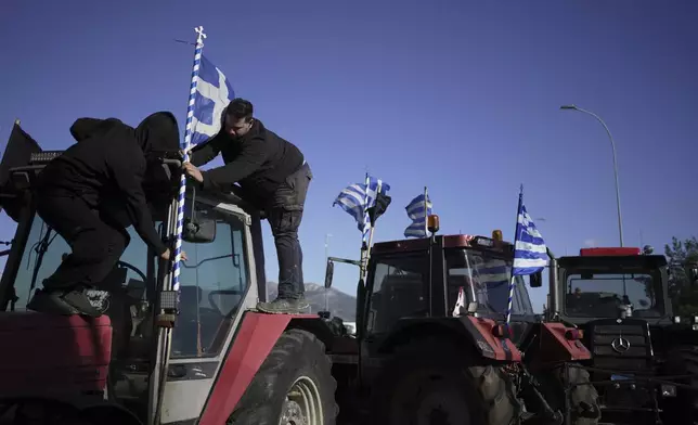 Farmers place a Greek flag on a tractor blocking the highway during a protest in Thiva, about 70 kilometers (44 miles) north of Athens, Greece, over delays in the payment of European Union-backed agricultural subsidies, Thursday, Jan. 8 2025. (AP Photo/Thanassis Stavrakis)