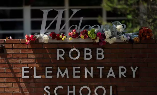 FILE - Flowers are placed around a welcome sign outside Robb Elementary School in Uvalde, Texas, May 25, 2022, to honor the victims killed in a shooting at the school. (AP Photo/Jae C. Hong, File)