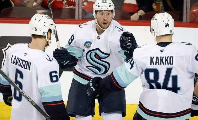 Seattle Kraken's Vince Dunn, centre, celebrates his goal with teammates during third period NHL hockey action against the Calgary Flames in Calgary, Alberta, Monday, Jan. 5, 2026. (Jeff McIntosh/The Canadian Press via AP)