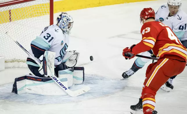 Seattle Kraken goalie Philipp Grubauer, left, lets in a goal by Calgary Flames' Adam Klapka (43) during first-period NHL hockey game action in Calgary, Alberta, Monday, Jan. 5, 2026. (Jeff McIntosh/The Canadian Press via AP)