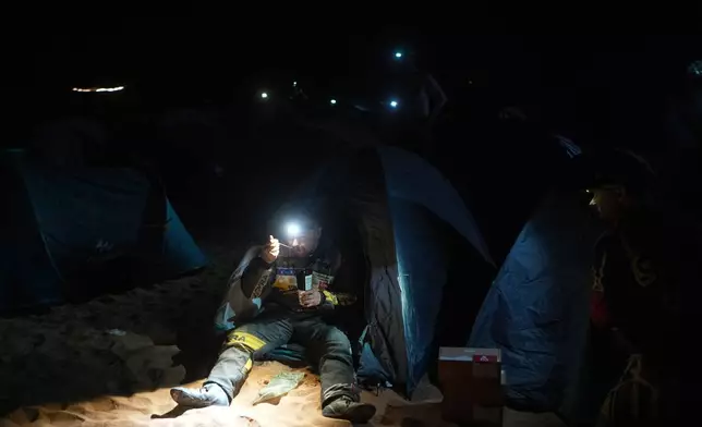 Mechanic Filip Skrobanek eats after he stopped for a bivouac following the fourth stage of the Dakar Rally between Alula and Hail, Saudi Arabia, Wednesday, Jan. 7, 2026. (AP Photo/Thibault Camus)