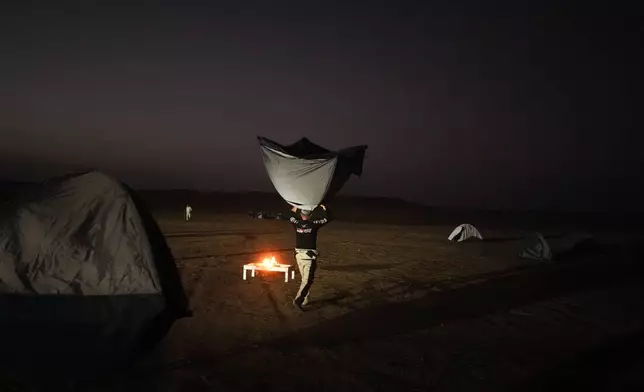 A driver carries his tent for a bivouac after the ninth stage of the Dakar Rally between Wadi Ad Dawasir and Bisha, Saudi Arabia, Tuesday, Jan.13, 2026. (AP Photo/Thibault Camus)