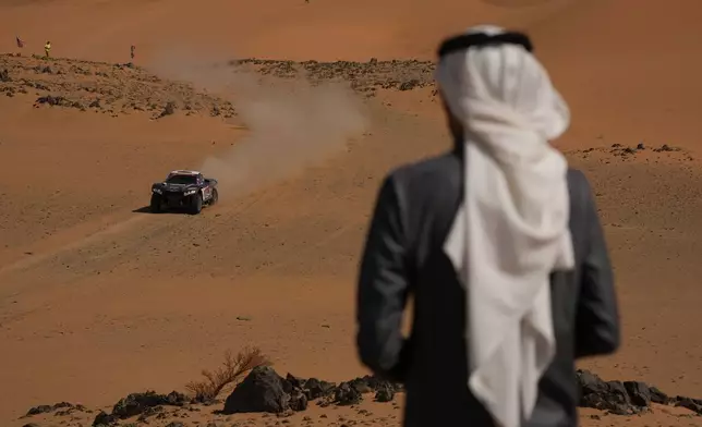 A spectator watches driver Brian Baragwanath and co-driver Leonard Cremer competing during the tenth stage of the Dakar Rally between Wadi Ad Dawasir and Bisha, Saudi Arabia, Wednesday, Jan.14, 2026. (AP Photo/Thibault Camus)