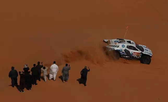 Spectators watch driver Denis Krotov and co-driver Konstantin Zhiltsov competing during the sixth stage of the Dakar Rally between Hail and Riyadh, Saudi Arabia, Friday, Jan. 9, 2026. (AP Photo/Thibault Camus)