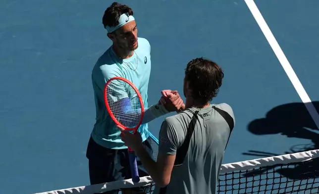 Lorenzo Musetti, left, of Italy, is congratulated by Taylor Fritz of the U.S. following his victory in their fourth round match at the Australian Open tennis championship in Melbourne, Australia, Monday, Jan. 26, 2026. (AP Photo/Mark Baker)