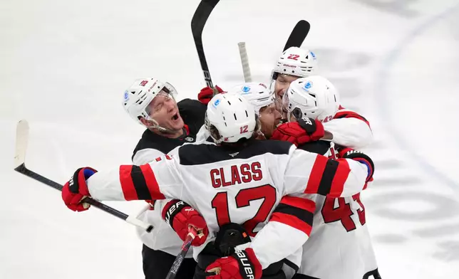 New Jersey Devils forward Ondrej Palat (18), forward Cody Glass (12), forward Connor Brown (16) defenseman Brett Pesce (22) and defenseman Luke Hughes (43) celebrate Hughes' goal against the Columbus Blue Jackets during the third period of an NHL hockey game in Columbus, Ohio, Wednesday, Dec. 31, 2025. (AP Photo/Paul Vernon)