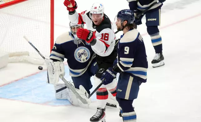 New Jersey Devils forward Ondrej Palat, center, celebrates between Columbus Blue Jackets goalie Jet Greaves, left, and defenseman Ivan Provorov after teammate defenseman Luke Hughes' goal during the third period of an NHL hockey game in Columbus, Ohio, Wednesday, Dec. 31, 2025. (AP Photo/Paul Vernon)