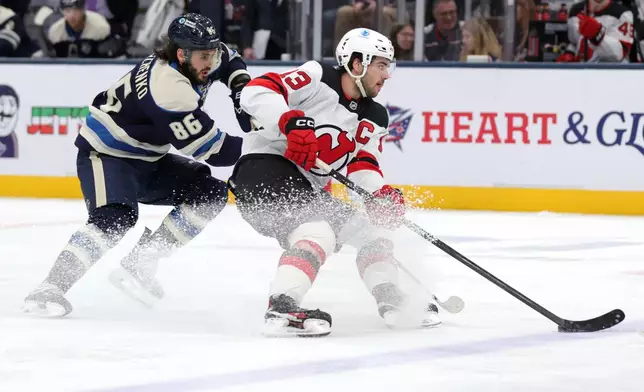 New Jersey Devils forward Nico Hischier, right, controls the puck in front of Columbus Blue Jackets forward Kirill Marchenko during the second period of an NHL hockey game in Columbus, Ohio, Wednesday, Dec. 31, 2025. (AP Photo/Paul Vernon)
