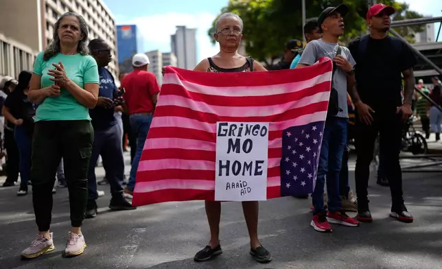 A government supporters displays a U.S. flag in Caracas, Venezuela, Sunday, Jan. 4, 2026. (AP Photo/Ariana Cubillos)