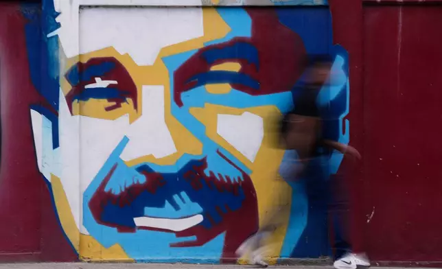 A pedestrian walks past a mural of Venezuelan President Nicolas Maduro Sunday, Jan. 4, 2026. (AP Photo/Matias Delacroix)