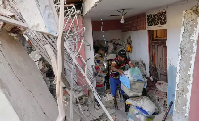 Jonathan Mayoral helps relatives clean up their apartment, which residents say was damaged during U.S. military operations to capture Venezuelan President Nicolás Maduro, in Catia La Mar, Venezuela, Sunday, Jan. 4, 2026. (AP Photo/Matias Delacroix)
