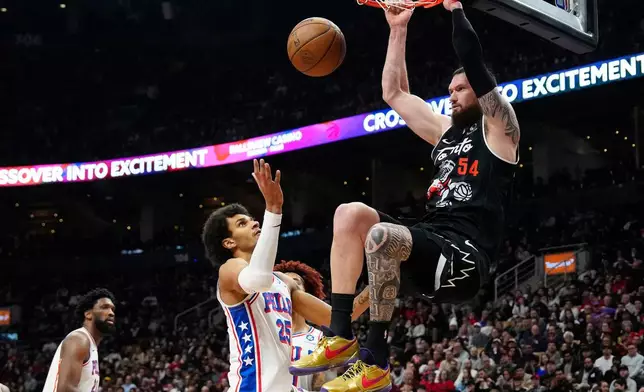 Toronto Raptors forward/center Sandro Mamukelashvili (54) dunks over Philadelphia 76ers forward Dominick Barlow (25) during the first half of an NBA basketball game in Toronto, Monday, Jan. 12, 2026. (Frank Gunn/The Canadian Press via AP)
