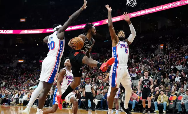 Toronto Raptors guard Immanuel Quickley (5) makes a pass under pressure from Philadelphia 76ers forward Adem Bona (30) and teammate Paul George (8) during first half NBA basketball action in Toronto, Monday, Jan. 12, 2026. (Frank Gunn/The Canadian Press via AP)
