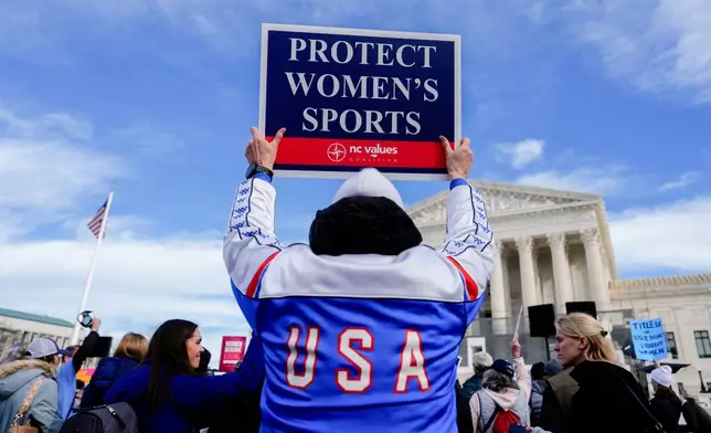A protester holds a sign outside the Supreme Court during arguments over state laws barring transgender girls and women from playing on school athletic teams, Tuesday, Jan. 13, 2026, in Washington. (AP Photo/Julia Demaree Nikhinson)