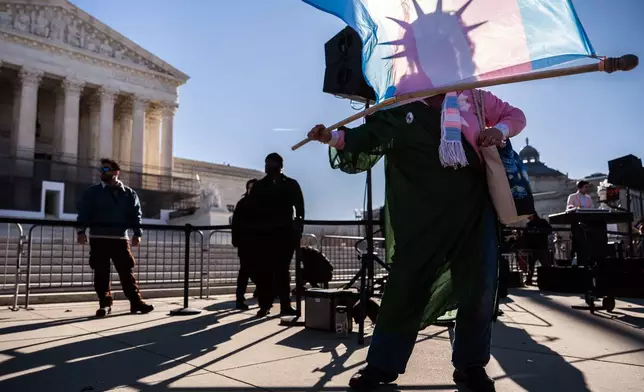 A protester dressed as the Statue of Liberty waves a transgender pride flag outside the Supreme Court as it hears arguments over state laws barring transgender girls and women from playing on school athletic teams, Tuesday, Jan. 13, 2026, in Washington. (AP Photo/Julia Demaree Nikhinson)