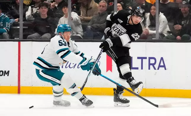Los Angeles Kings left wing Kevin Fiala, right, passes the puck while under pressure from San Jose Sharks left wing Jeff Skinner during the first period of an NHL hockey game Wednesday, Jan. 7, 2026, in Los Angeles. (AP Photo/Mark J. Terrill)
