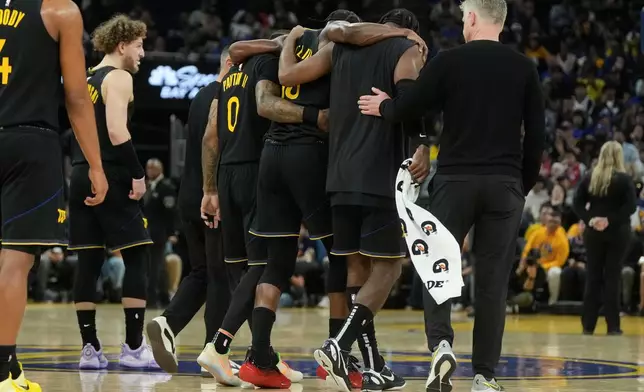 Golden State Warriors forward Jimmy Butler III, middle, is helped off the floor by teammates during the second half of an NBA basketball game against the Miami Heat in San Francisco, Monday, Jan. 19, 2026. (AP Photo/Jeff Chiu)
