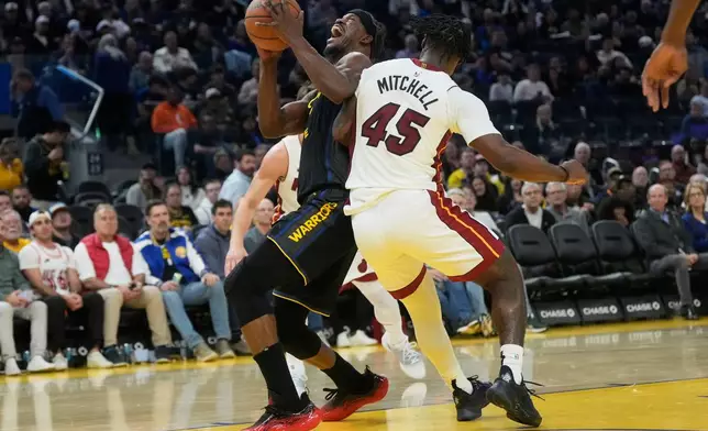Golden State Warriors forward Jimmy Butler III, left, reacts after contact with Miami Heat guard Davion Mitchell (45) during the second half of an NBA basketball game in San Francisco, Monday, Jan. 19, 2026. (AP Photo/Jeff Chiu)