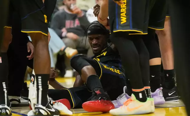 Golden State Warriors forward Jimmy Butler III, middle, is helped up by teammates during the second half of an NBA basketball game against the Miami Heat in San Francisco, Monday, Jan. 19, 2026. (AP Photo/Jeff Chiu)