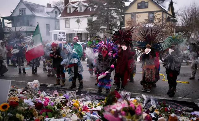 Aztec dancers stand before a makeshift memorial near the site where Renee Good was fatally shot by an ICE officer earlier in the week, in Minneapolis, Saturday, Jan. 10, 2026. (AP Photo/John Locher)