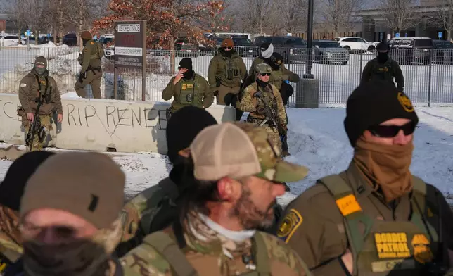 Federal agents look on as protesters gather during a rally for Renee Good, who was fatally shot by an ICE officer earlier in the week, Saturday, Jan. 10, 2026, in Minneapolis. (AP Photo/Adam Gray)