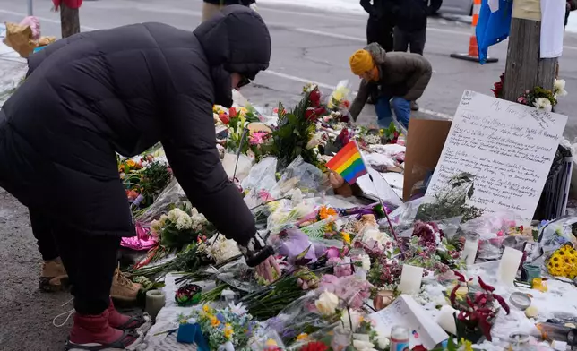 People place flowers for a memorial at the site where Renee Good was fatally shot by an ICE agent in Minneapolis, Saturday, Jan. 10, 2026. (AP Photo/Jen Golbeck)