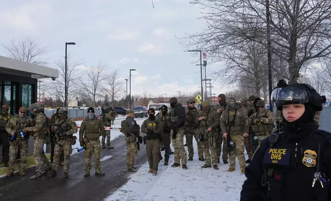 Federal agents stand outside the Bishop Henry Whipple Federal Building as protesters gather in Minneapolis, Saturday, Jan. 10, 2026. (AP Photo/Adam Gray)