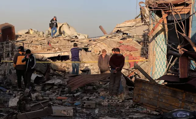 People check the site where an Israeli strike destroyed a building at a commercial district, in the southern port city of Sidon, Lebanon, Tuesday, Jan. 6, 2026. (AP Photo/Mohammed Zaatari)