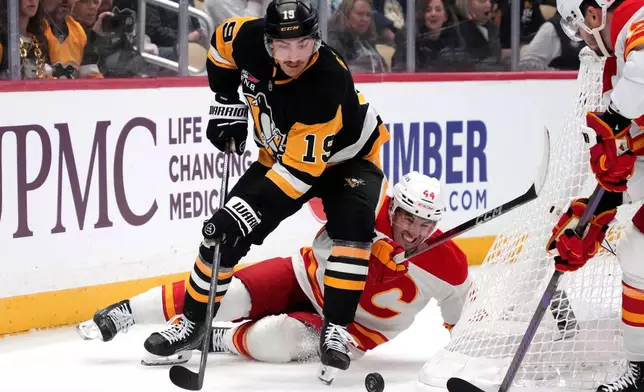 Pittsburgh Penguins' Connor Dewar (19) checks Calgary Flames' Joel Hanley (44) off the puck during the second period of an NHL hockey game in Pittsburgh, Saturday, Jan. 10, 2026. (AP Photo/Gene J. Puskar)