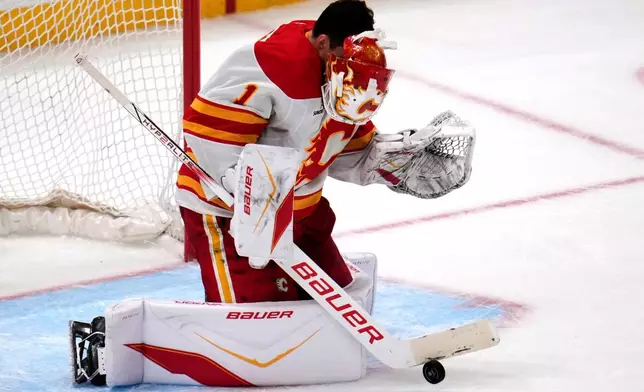 Calgary Flames goaltender Devin Cooley has his mask knocked off by a shot on goal during the first period of an NHL hockey game against the Pittsburgh Penguins in Pittsburgh, Saturday, Jan. 10, 2026. (AP Photo/Gene J. Puskar)