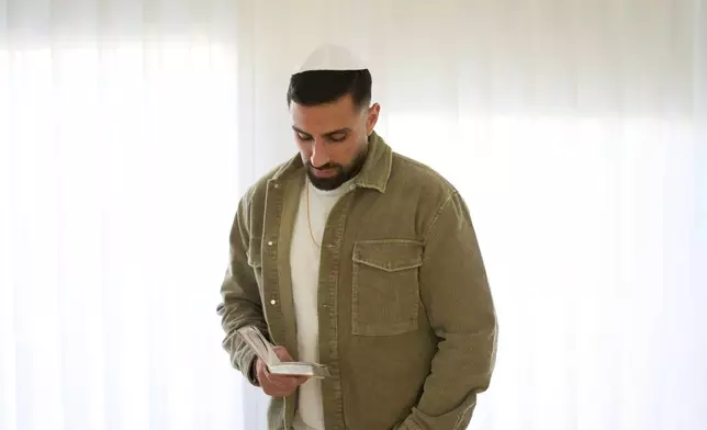 Segev Kalfon, an Israeli hostage who spent two years in captivity in a Hamas tunnel and was released from the Gaza Strip in a ceasefire deal on Oct. 13, reads from a holy book on at his home in Dimona, southern Israel, Tuesday, Dec. 23, 2025. (AP Photo/Ariel Schalit)
