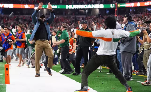 Former NFL football players Ray Lewis, left, and Michael Irvin react after Miami running back Charmar Brown, not visible, scored a rushing touchdown during the second half of the Cotton Bowl College Football Playoff quarterfinal game against Ohio State Wednesday, Dec. 31, 2025, in Arlington, Texas. (AP Photo/Julio Cortez)
