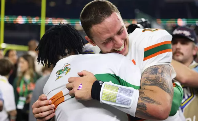 Miami quarterback Carson Beck, right, is hugged by former NFL player Michael Irvin following the Cotton Bowl College Football Playoff quarterfinal game against Ohio State Wednesday, Dec. 31, 2025, in Arlington, Texas. (AP Photo/Gareth Patterson)
