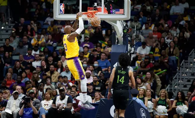 Los Angeles Lakers forward LeBron James (23) dunks next to New Orleans Pelicans guard Micah Peavy (14) during the first half of an NBA basketball game in New Orleans, Tuesday, Jan. 6, 2026. (AP Photo/Matthew Hinton)