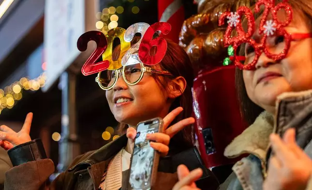 People pose for photographs at Lan Kwai Fong to celebrate the start of 2026 in the Central district of Hong Kong, on Wednesday, Dec. 31, 2025. (AP Photo/Chan Long Hei)
