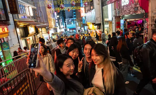 People take selfies at Lan Kwai Fong to celebrate the start of 2026 in the Central district of Hong Kong, on Wednesday, Dec. 31, 2025. (AP Photo/Chan Long Hei)