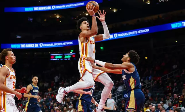 Atlanta Hawks forward Jalen Johnson, center, shoots against New Orleans Pelicans guard Jordan Poole, right, during the first half of an NBA basketball game, Wednesday, Jan. 7, 2026, in Atlanta. (AP Photo/Colin Hubbard)