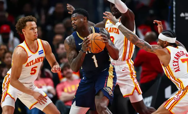 Atlanta Hawks guard Dyson Daniels, left, forward Mouhamed Gueye, center, and guard Nickeil Alexander-Walker, right, defend against New Orleans Pelicans forward Zion Williamson (1) during the first half of an NBA basketball game, Wednesday, Jan. 7, 2026, in Atlanta. (AP Photo/Colin Hubbard)