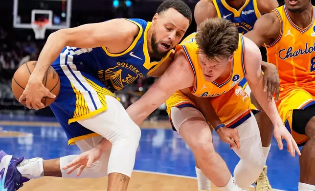 Golden State Warriors guard Stephen Curry vies for the ball with Charlotte Hornets guard Kon Knueppel during the second half of an NBA basketball game, Wednesday, Dec. 31, 2025, in Charlotte, N.C. (AP Photo/Chris Carlson)