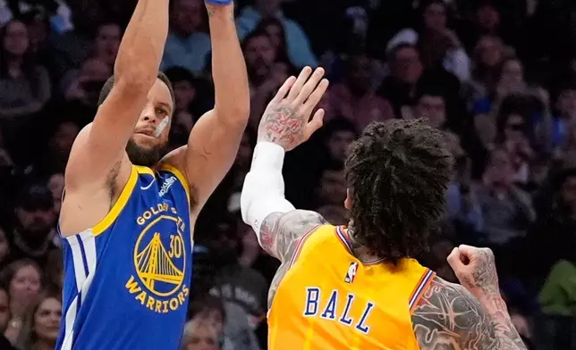 Golden State Warriors guard Stephen Curry shoots over Charlotte Hornets guard Lamelo Ball during the first half of an NBA basketball game, Wednesday, Dec. 31, 2025, in Charlotte, N.C. (AP Photo/Chris Carlson)