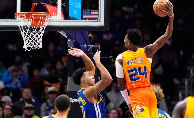 Charlotte Hornets forward Brandon Miller dunks over Golden State Warriors forward Trayce Jackson-Davis during the first half of an NBA basketball game, Wednesday, Dec. 31, 2025, in Charlotte, N.C. (AP Photo/Chris Carlson)