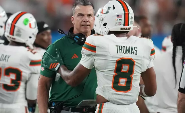 Miami head coach Mario Cristobal talks with defensive back Jakobe Thomas (8) during the second half of the Fiesta Bowl NCAA college football playoff semifinal game against Mississippi, Thursday, Jan. 8, 2026, in Glendale, Ariz. (AP Photo/Rick Scuteri)