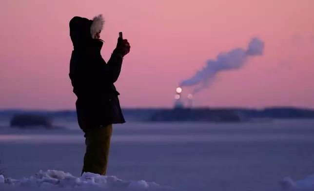 Emma Nadeau, of North Yarmouth, Maine, photographs the pre-dawn scene overlooking Casco Bay on a 1-degree F. morning, Saturday, Jan. 24, 2026, in Portland, Maine. (AP Photo/Robert F. Bukaty)