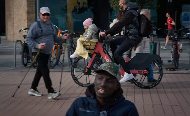 Alioune Beye, originally from Senegal, speaks during an interview with The Associated Press, while people stroll along the Barcelona seafront promenade, Spain, Thursday, Jan. 29, 2026. (AP Photo/Emilio Morenatti)