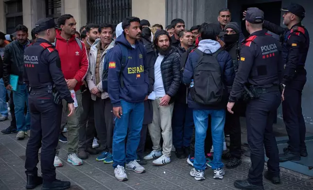 A crowd of Pakistanis gathers at the entrance of the Pakistani consulate in Barcelona, Spain, Thursday, Jan. 29, 2026, following the Spanish government's decision to grant residency and work permits to potentially hundreds of thousands of immigrants. (AP Photo/Emilio Morenatti)