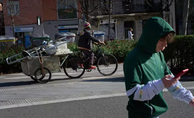 Mamadou, from Senegal, transports scrap metal and discarded electrical appliances on his bicycle after salvaging them from trash containers, as he heads to sell them by weight in Barcelona, Spain, Friday, Jan. 30, 2026. (AP Photo/Emilio Morenatti)