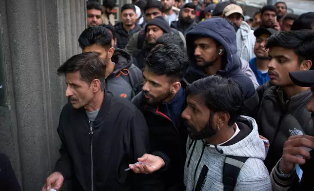 A crowd of Pakistanis gathers at the entrance of the Pakistani consulate in Barcelona, Spain, Thursday, Jan. 29, 2026, following the Spanish government's decision to grant residency and work permits to potentially hundreds of thousands of immigrants. (AP Photo/Emilio Morenatti)