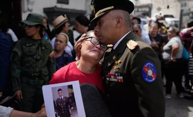 A military officer comforts Ramona Palma, the mother of Venezuelan soldier Cesar Garcia, who was killed in a U.S. raid that captured Venezuelan President Nicolas Maduro, after Garcia's wake in Caracas, Venezuela, Wednesday, Jan. 7, 2026. (AP Photo/Matias Delacroix)